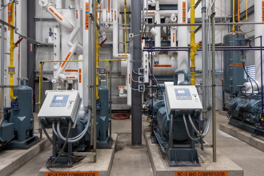 Image of pipes and control panels inside a large warehouse